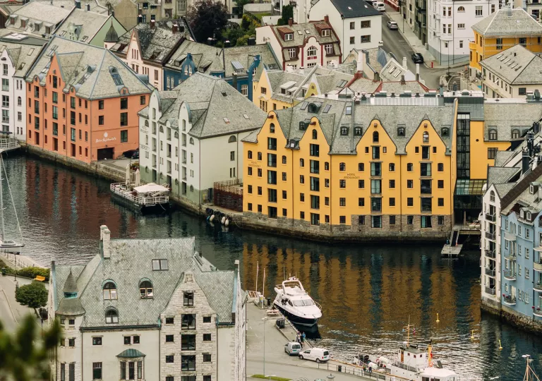 Exterior view of orange and black hotel building, by a river in the middle of a town