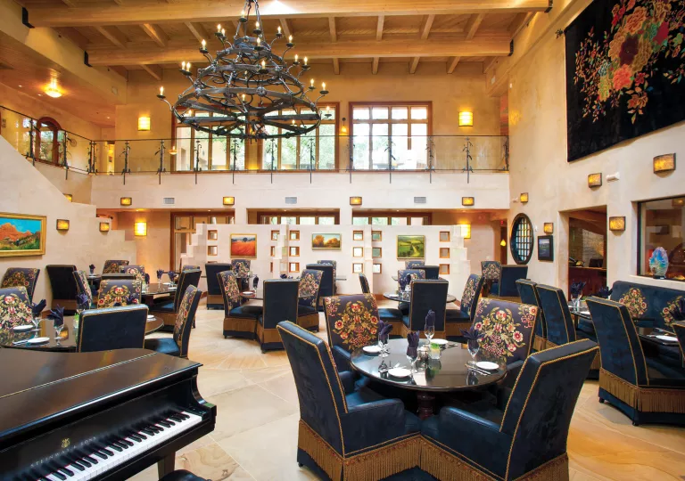Indoor dining hall with large, blue chairs and a piano to the left