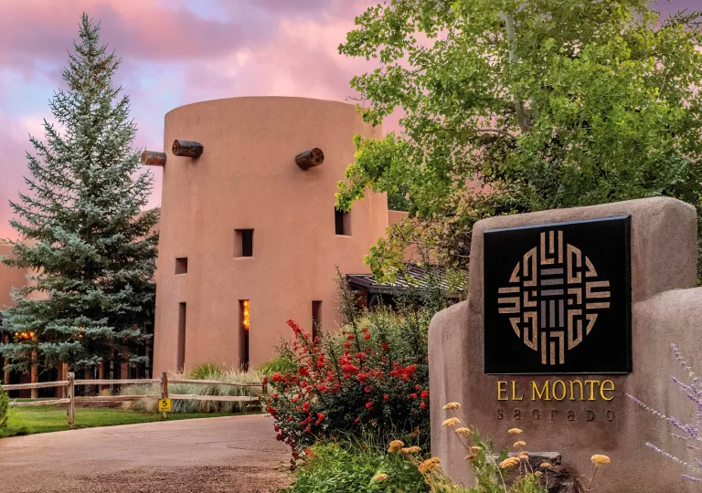 Exterior view of a clay hotel building with a stone "El Monte" sign