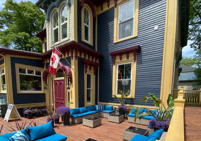 Exterior view of blue and yellow house with a Canadian flag in front