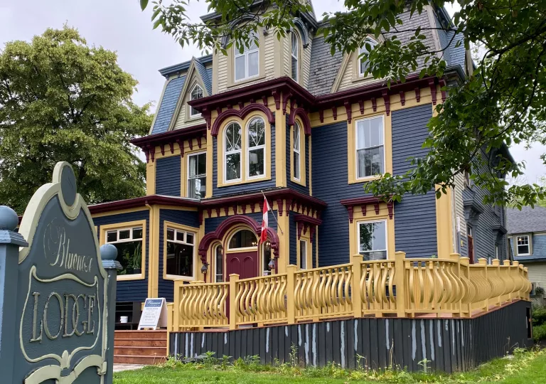 Exterior view of blue and yellow hotel building with a yellow gate in front