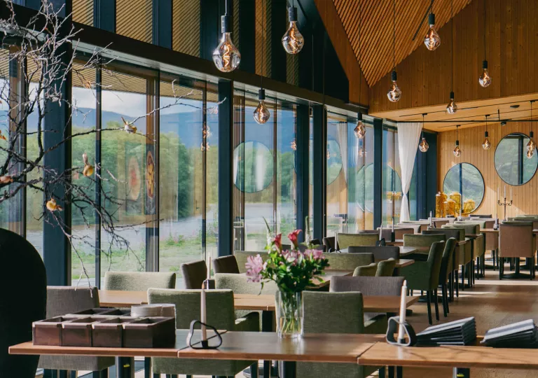 Cafe and seating area with green and gray cushioned chairs, and large windows to the left