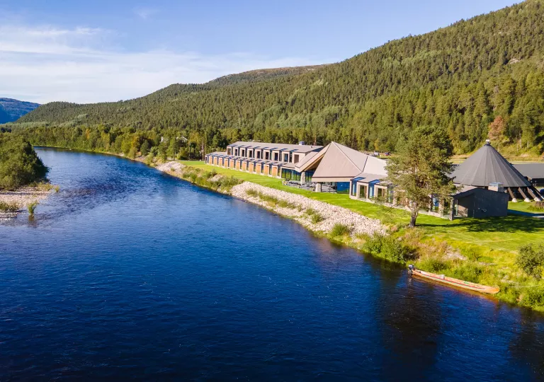 Long building along a river with a forest in the background