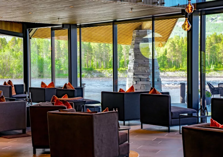 Seating area with cushioned chairs looking out to a river through large glass walls