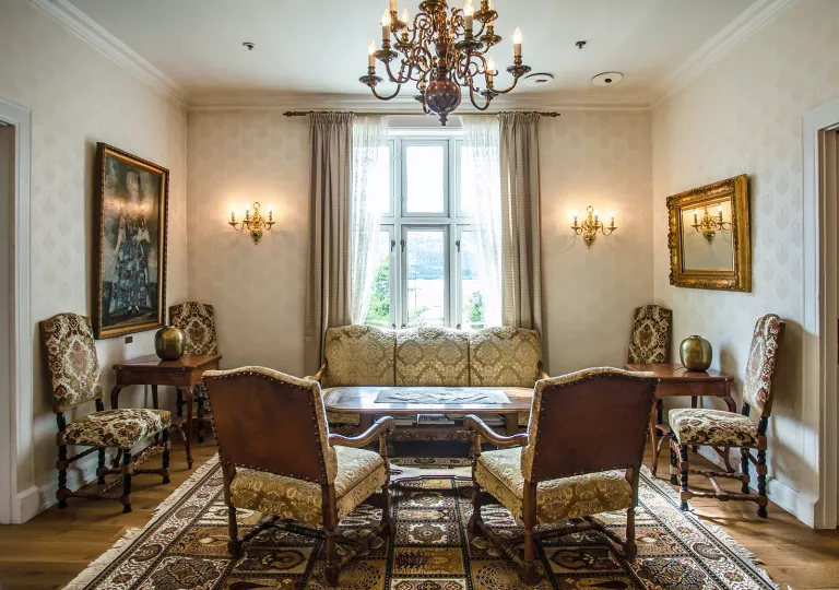 Lounge and seating area with patterned cushioned chairs, with paintings on the walls