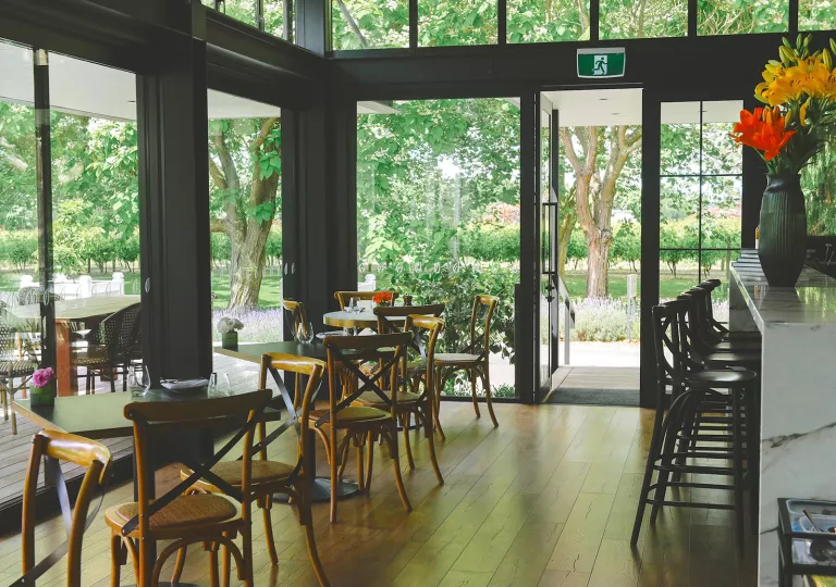 Dining area with wooden tables and chairs, in a room with large windows