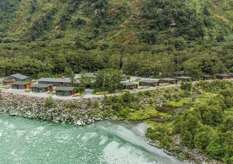 Cabin buildings surrounded by thick forest, with the ocean to the left