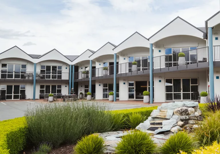 Exterior view of white hotel building with rooms and large windows