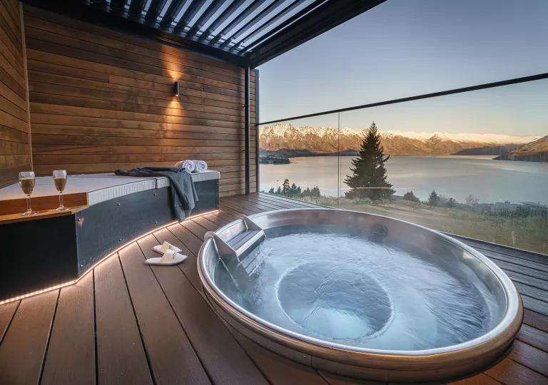 Outdoor hot tub overlooking a lake and snow-capped mountains