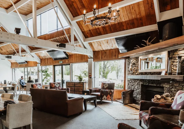 Lodge building's lounge with a stone fireplace and cushioned chairs