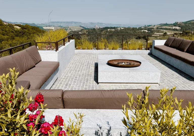 Rooftop patio with a large, brown couch and fire pit in the center