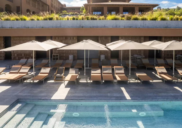 Outdoor pool with reclining, beige chairs surrounding