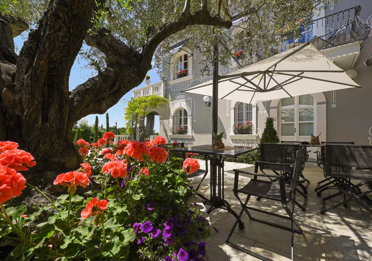 Outdoor patio and garden with black dining tables and chairs, and white umbrellas