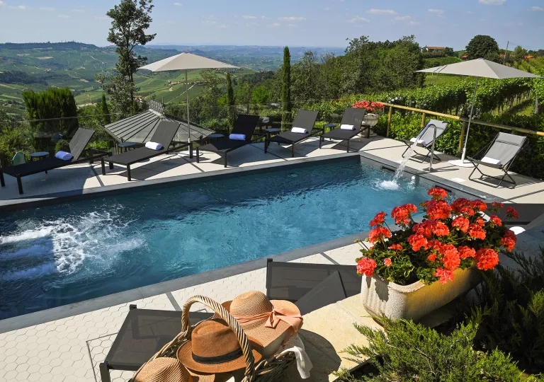 Outdoor pool surrounded by reclining chairs and a valley in the distance