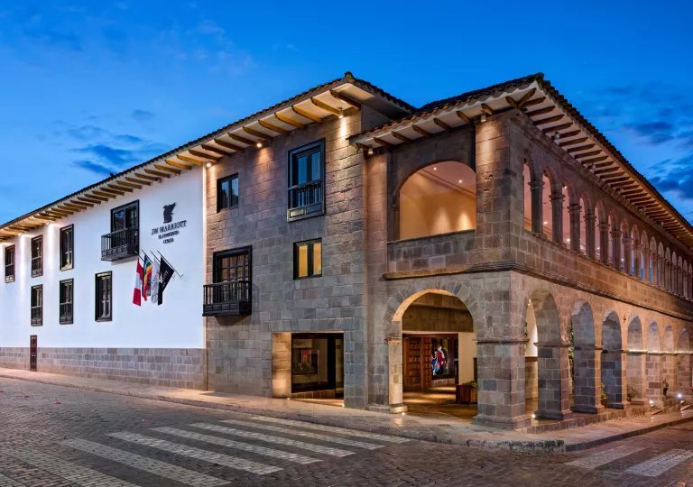 Exterior view of stone hotel building with small archways and empty road in front