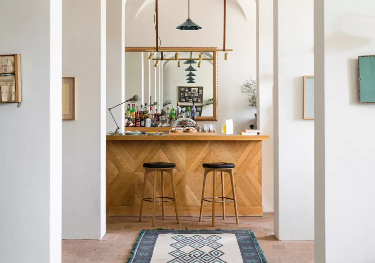 White hallway leading to a bar counter and two wooden stools