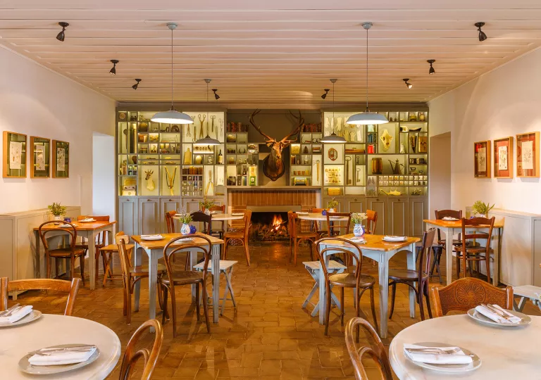 Dining area with wooden tables and chairs, with a deer head hanging on the wall