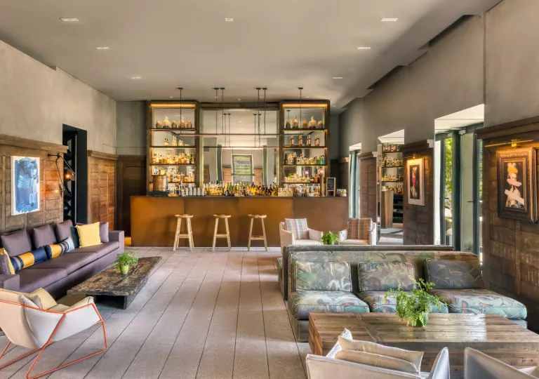 Indoor lounge with a bar in the back, and cushioned chairs along the walls