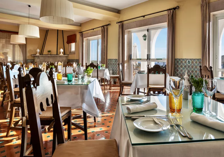 Restaurant with white dining tables and large windows in the background