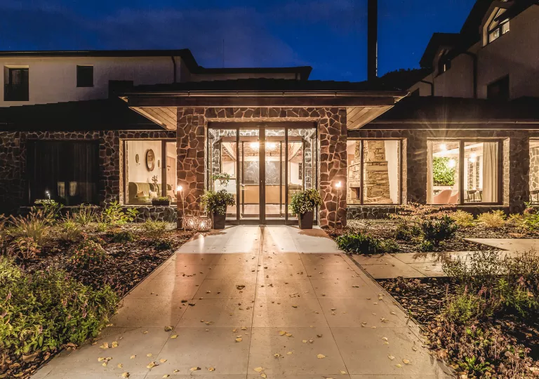 Exterior view of illuminated building with stone pillars and large windows