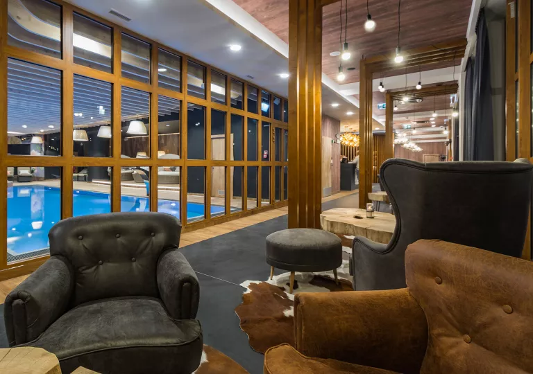 Long hallways with cushioned chairs and an indoor pool in front