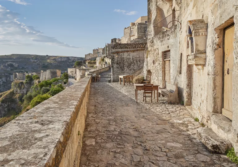 Exterior patio of rustic, stone building on a cliff, with other stone buildings in the background