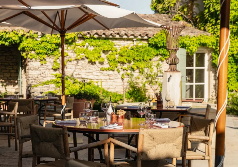 Outdoor patio with dining tables and umbrellas, with wine glasses on each table