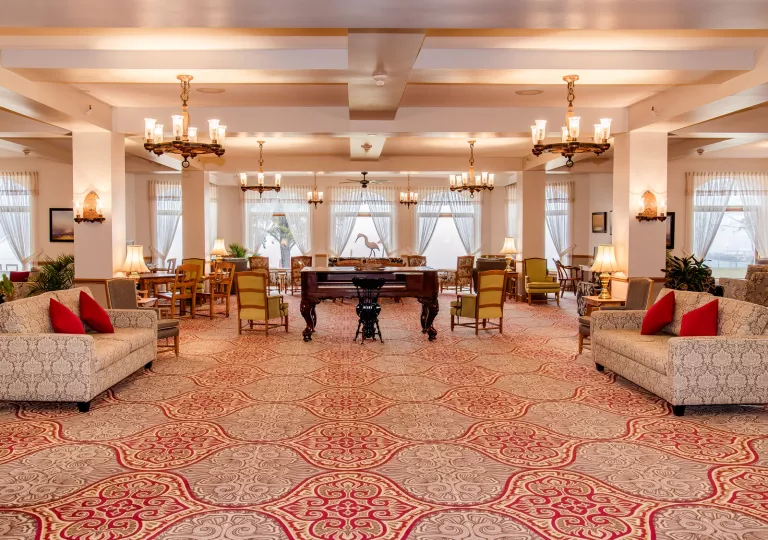 Large banquet hall with cushioned chairs and a piano in the center