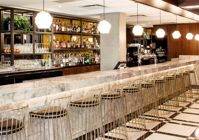 Bar and lounge with marble counters and shelving full of alcohol