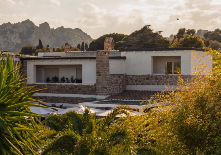 Exterior view of white and stone building with trees in front