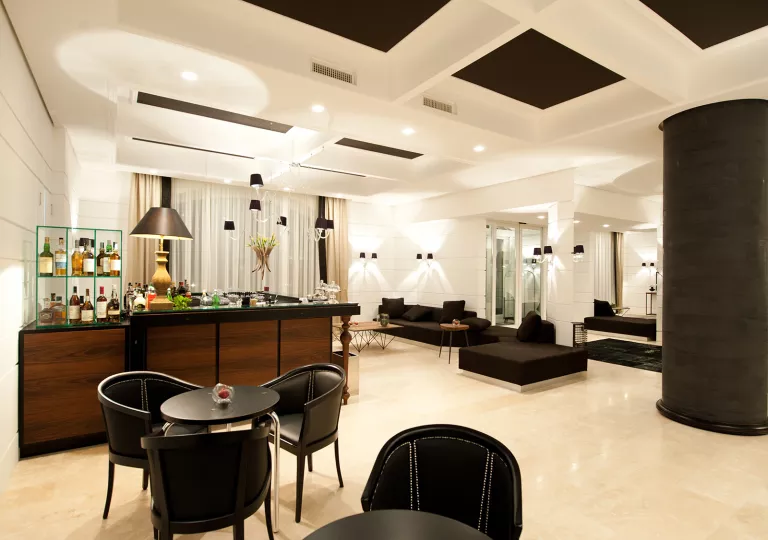 Bar and lounge with black chairs and tables, and a bar counter in the back