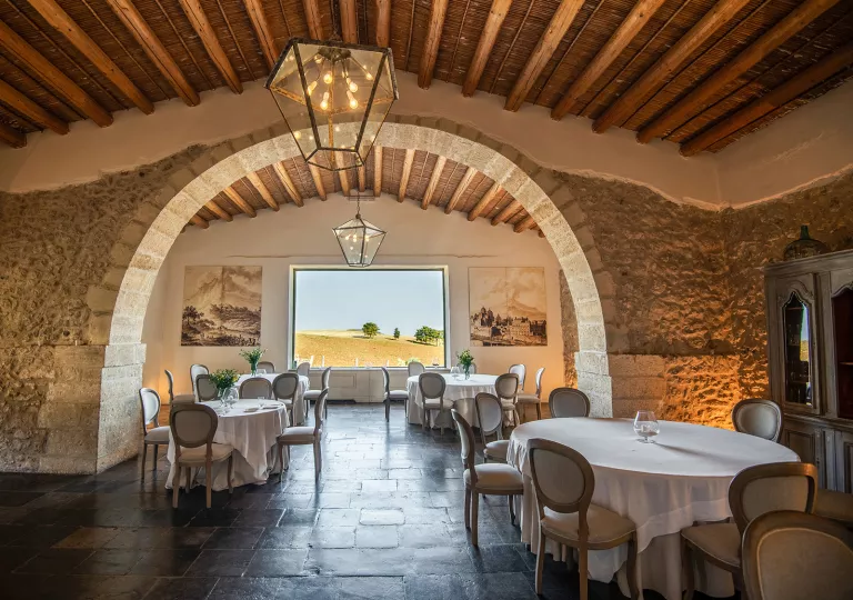 Indoor dining hall with circular tables and stone walls