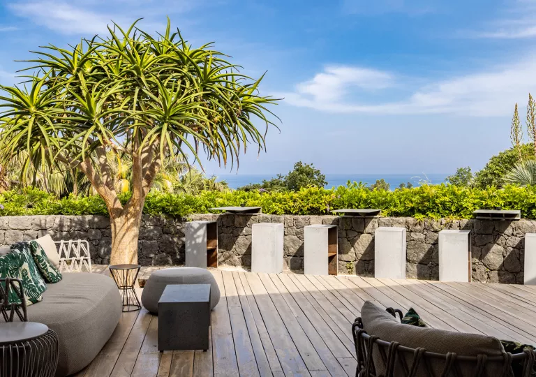Outdoor patio with cushioned, gray chairs and cement stools and tables