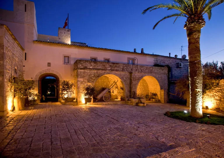 Exterior view of large stone and brick building with an illuminated courtyard
