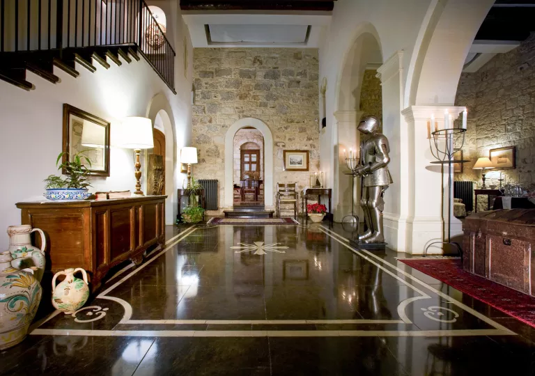 Interior view of large room with stone walls, and black-tiled floor and an soldier armor statue to the right