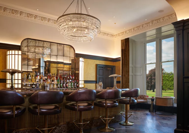 Bar and lounge with bottles of alcohol along the wall and large light fixtures from the ceiling