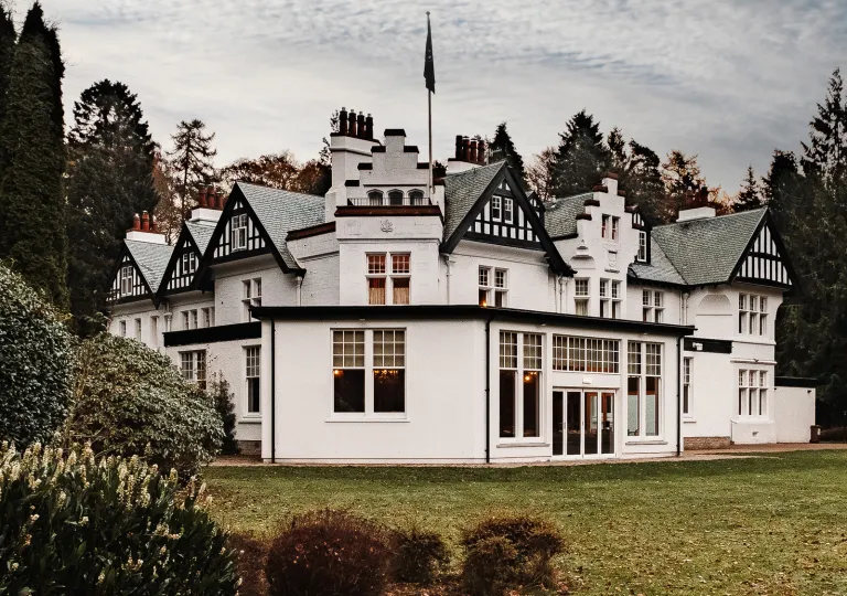 Exterior view of white and black building with a grass field in front