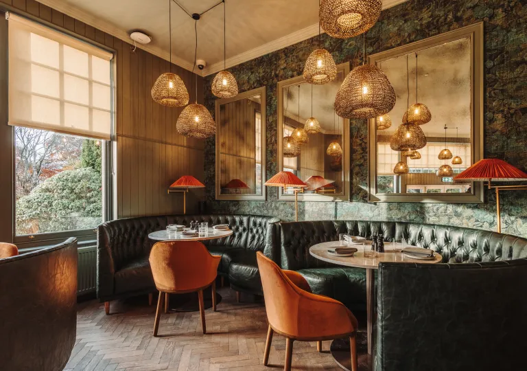 Dining area with green, circular sofas surrounding circular tables