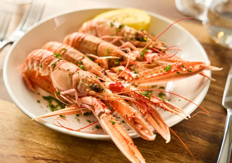 Plate of cooked prawns with a lemon wedge on the right