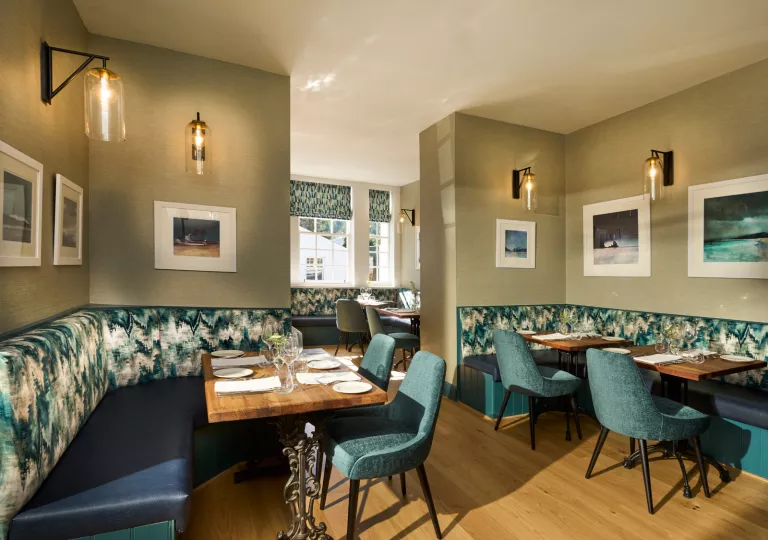 Dining hall with blue and green chairs and sofas around tables