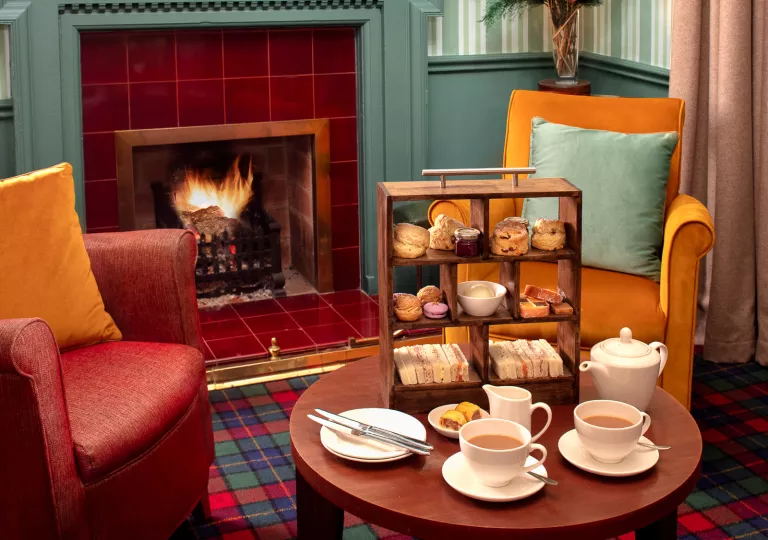 Two chairs next to a small coffee table full of pastries and cups of coffee