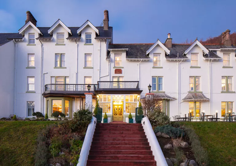 Exterior view of white hotel building with a red staircase in front