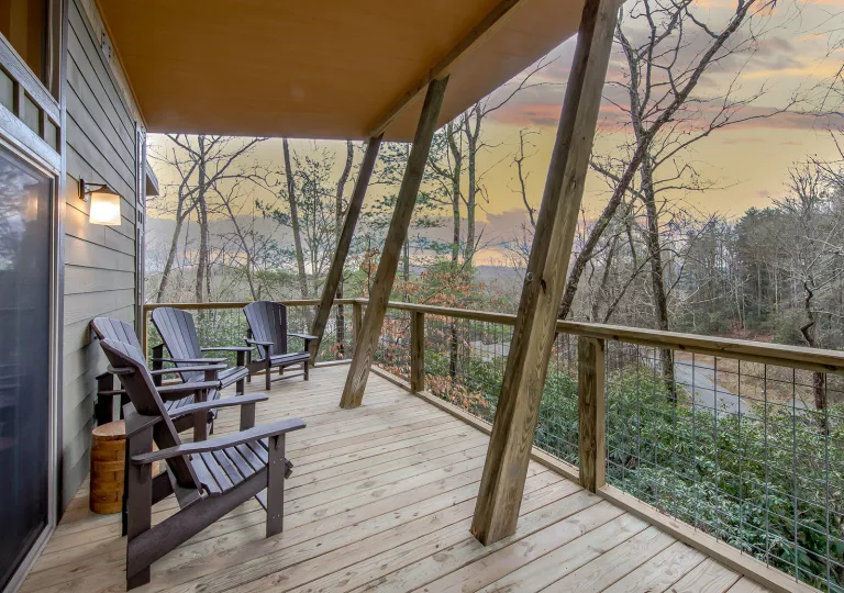 Outdoor patio of a wooden cabin, looking out towards a forest