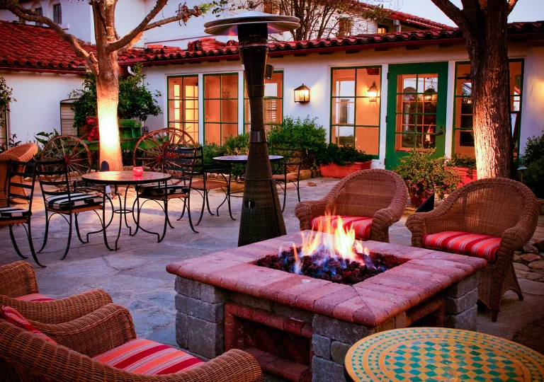 Outdoor patio with a stone firepit and metal chairs for seating