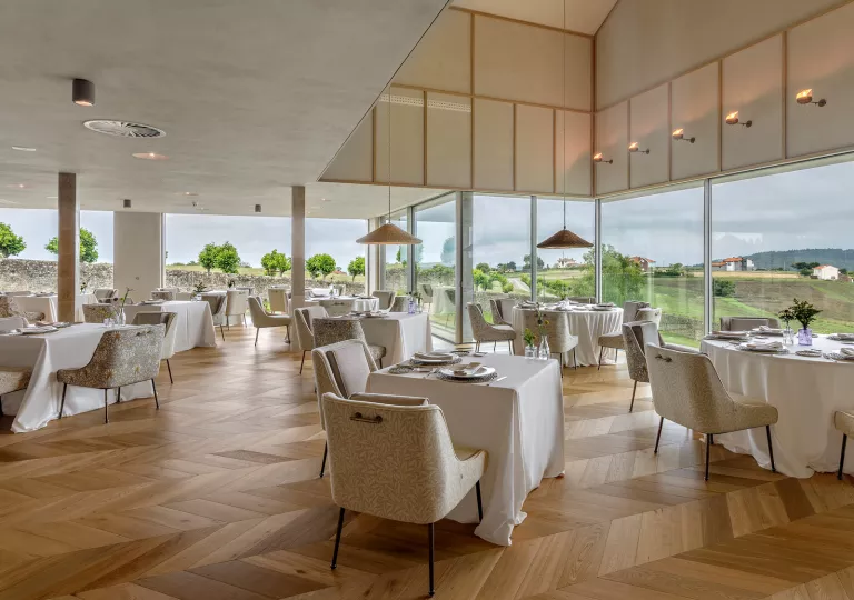 Dining hall with square white tables and large windows along the walls