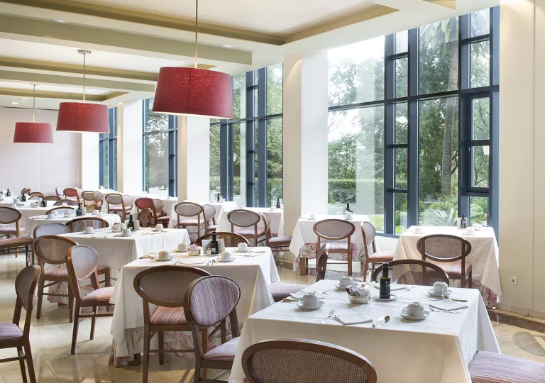 Dining hall with white, square tables and cushioned wooden chairs