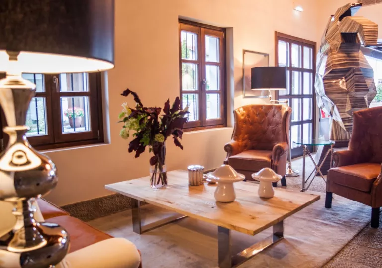 Seating area with leather couches in front of a small, wooden table with plants on top