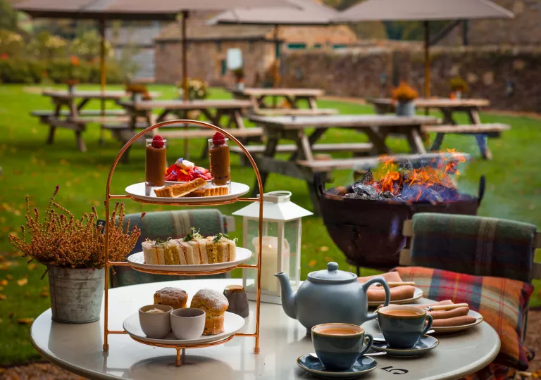 Table outdoor with tea and pastries, with benches in the background