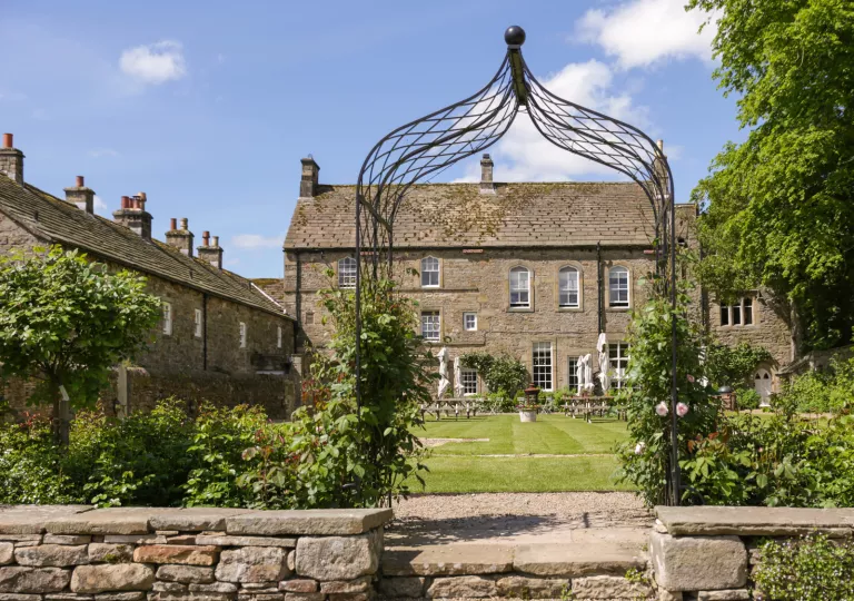 Outdoor view of a stone building with a large grass field and large umbrellas