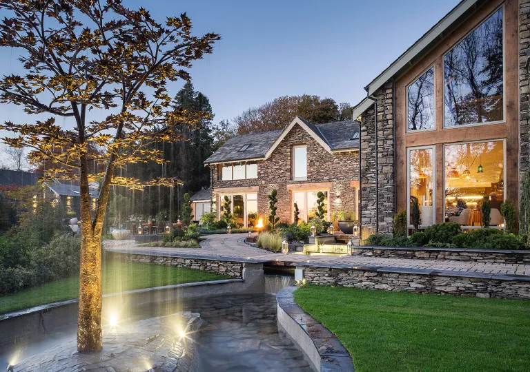 Exterior view of stone house with a fountain and tree in front